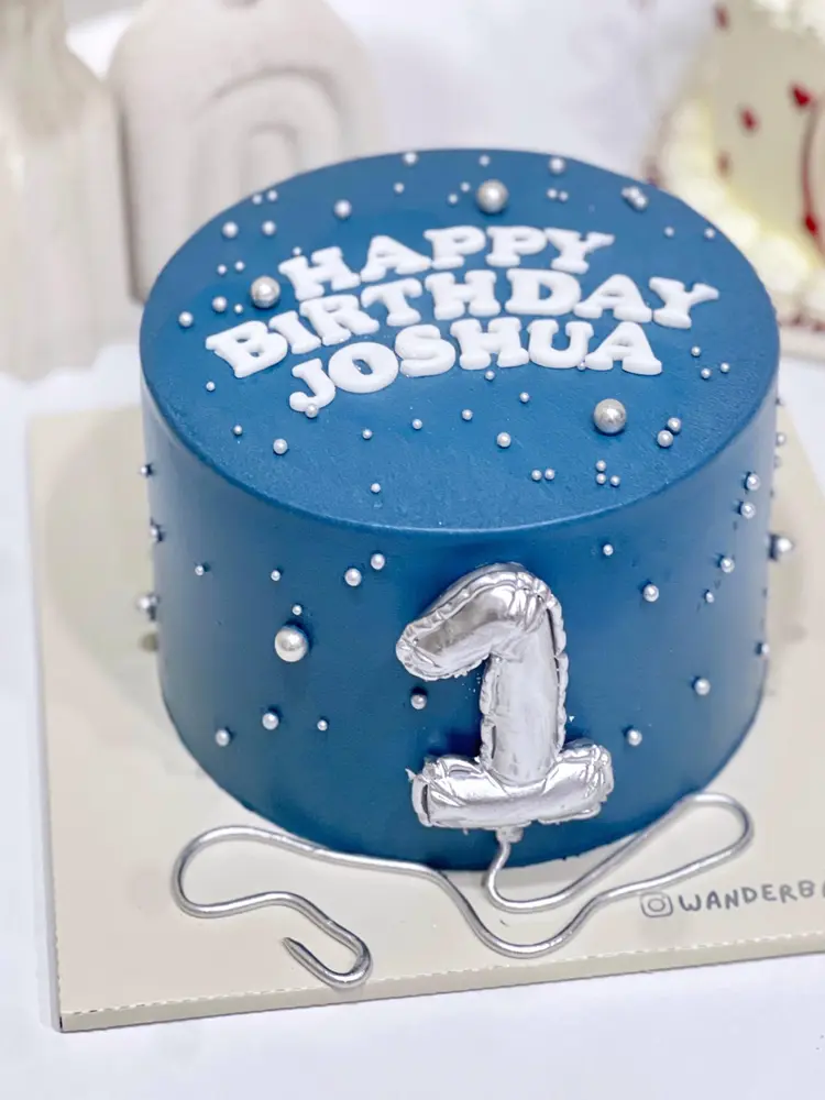Cake biru navy bertabur mutiara dengan balon angka 1 warna perak