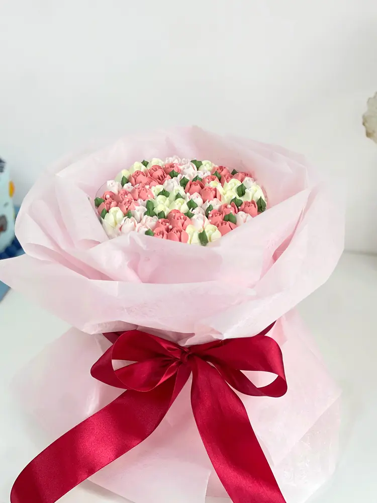 Bouquet cake bunga merah muda dan hijau dibungkus kertas pink dengan pita merah